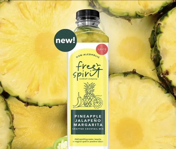 Pineapple Jalapeño Margarita bottle on a bed of its fresh ingredients